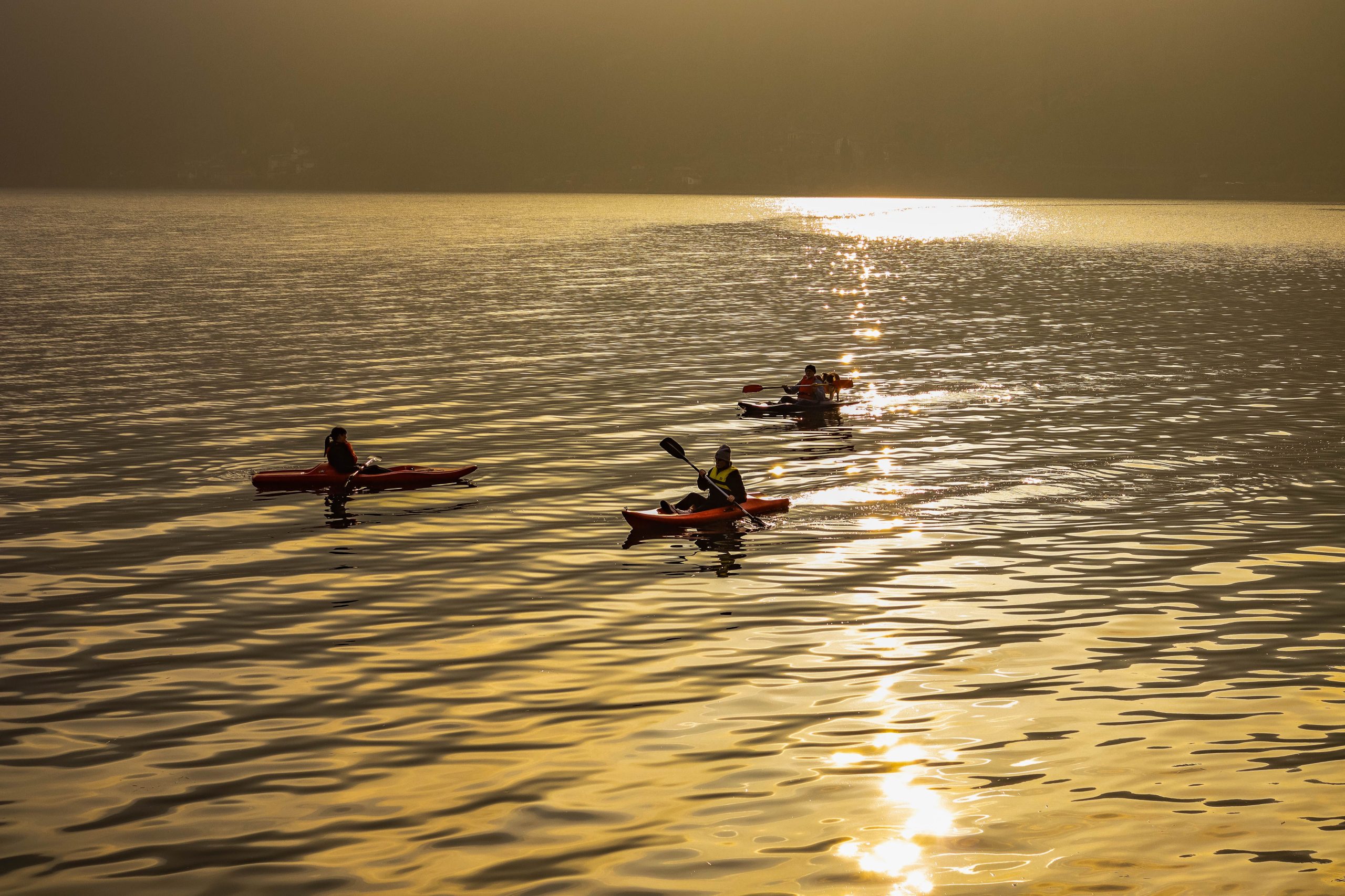 Trois personnes en canoë au coucher soleil
