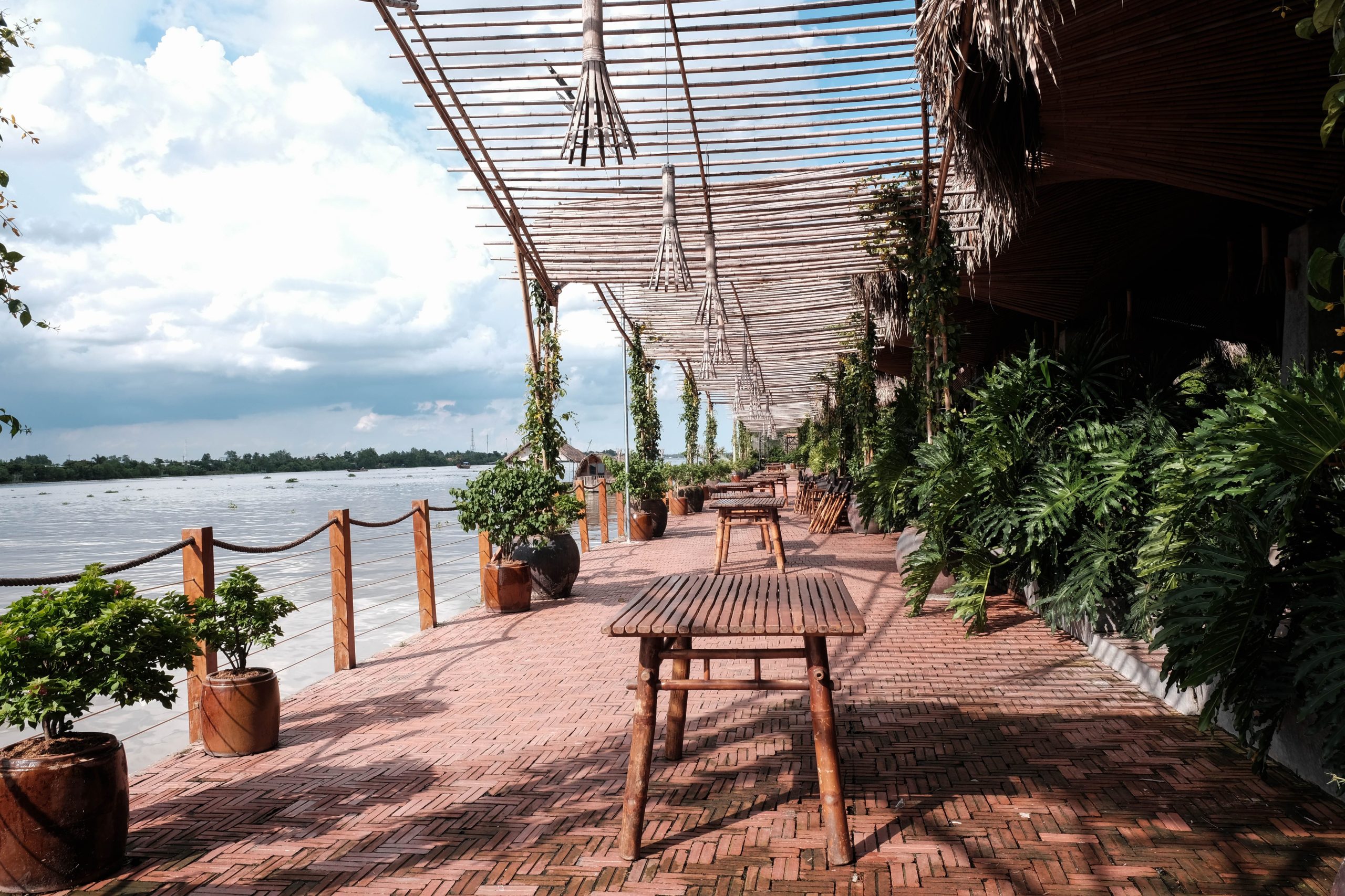 Terrasse ensoleillée au bord de l'eau avec tables en bois
