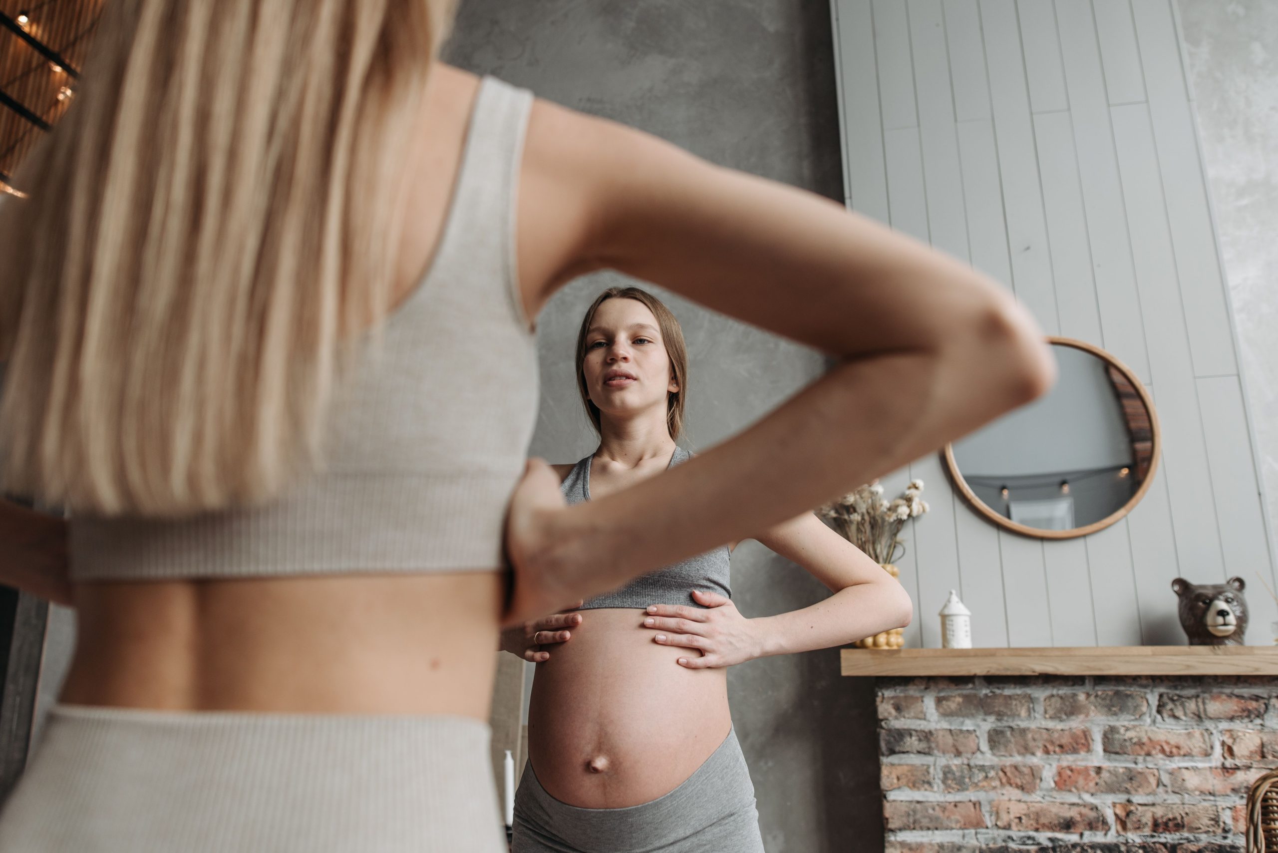 Femme enceinte pratiquant exercices doux devant miroir.