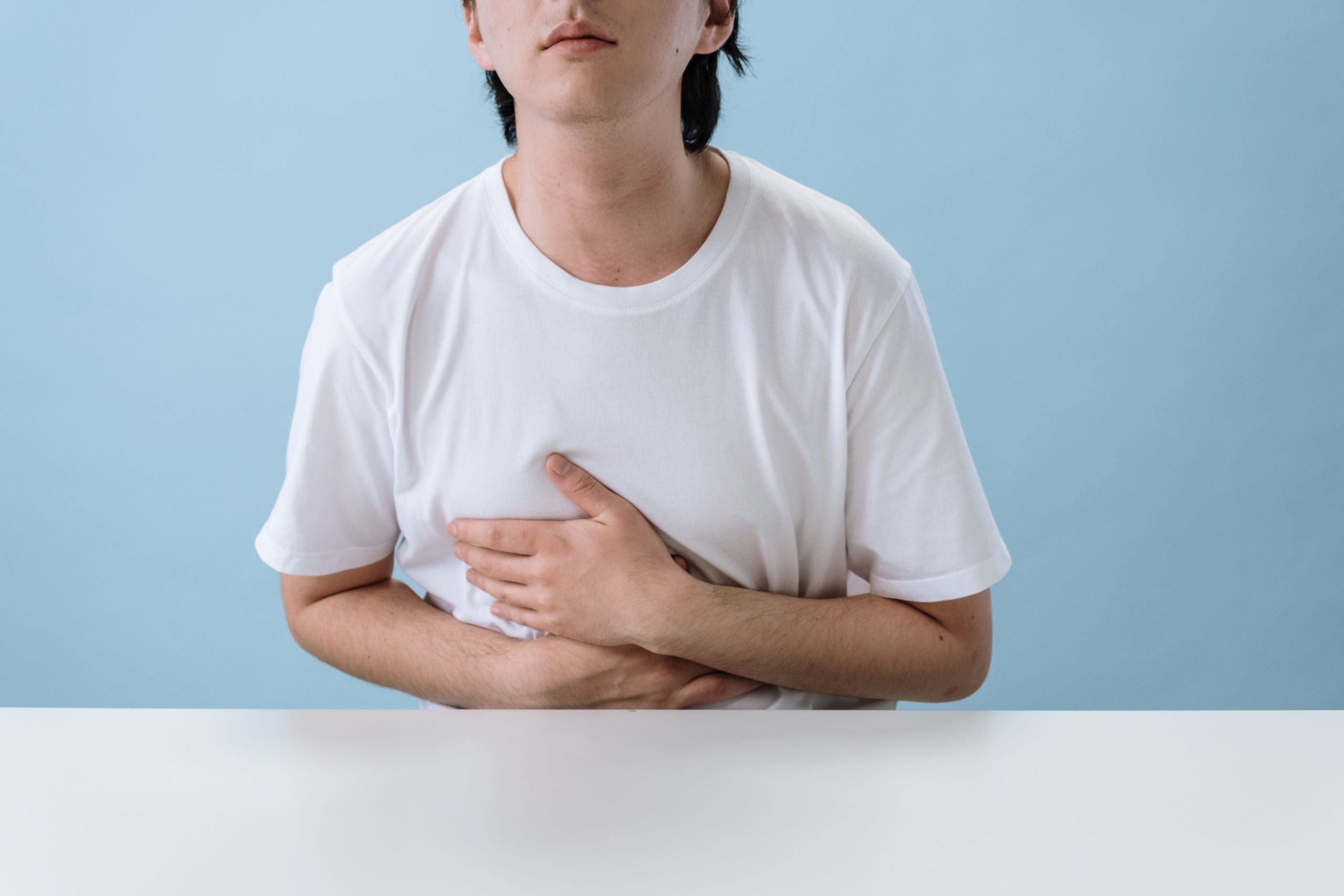 Homme en blanc se tenant le ventre douloureux