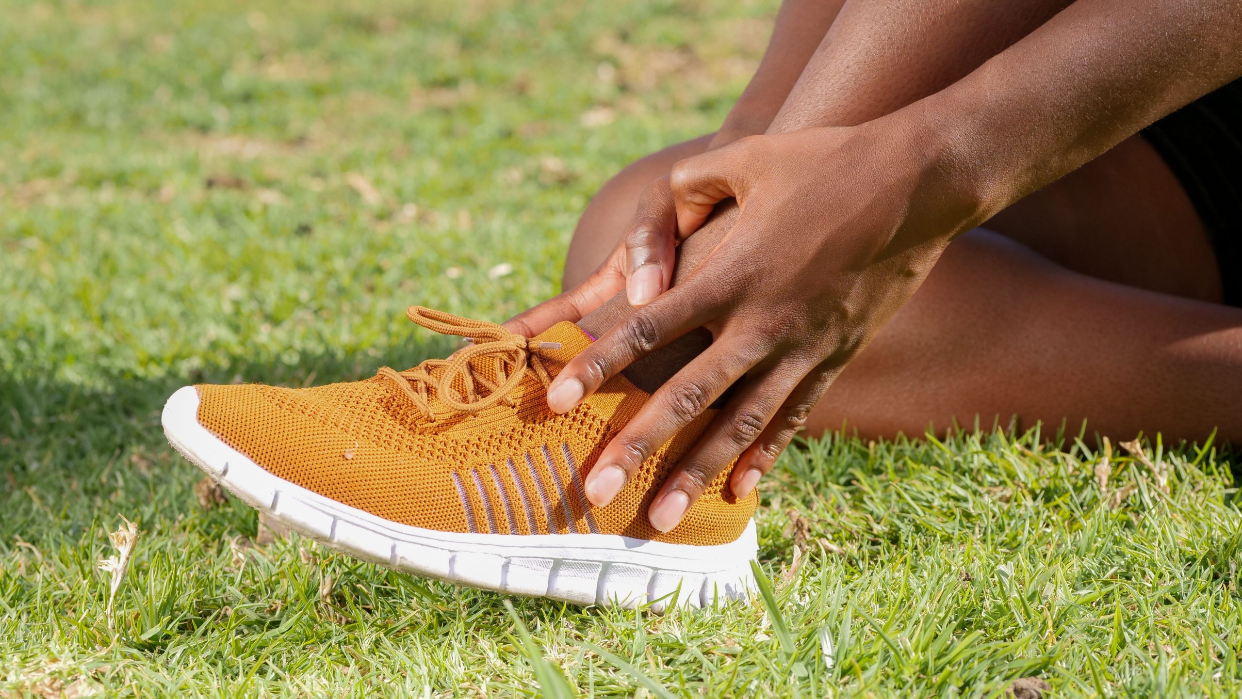 Personne tenant sa cheville avec sneaker orange