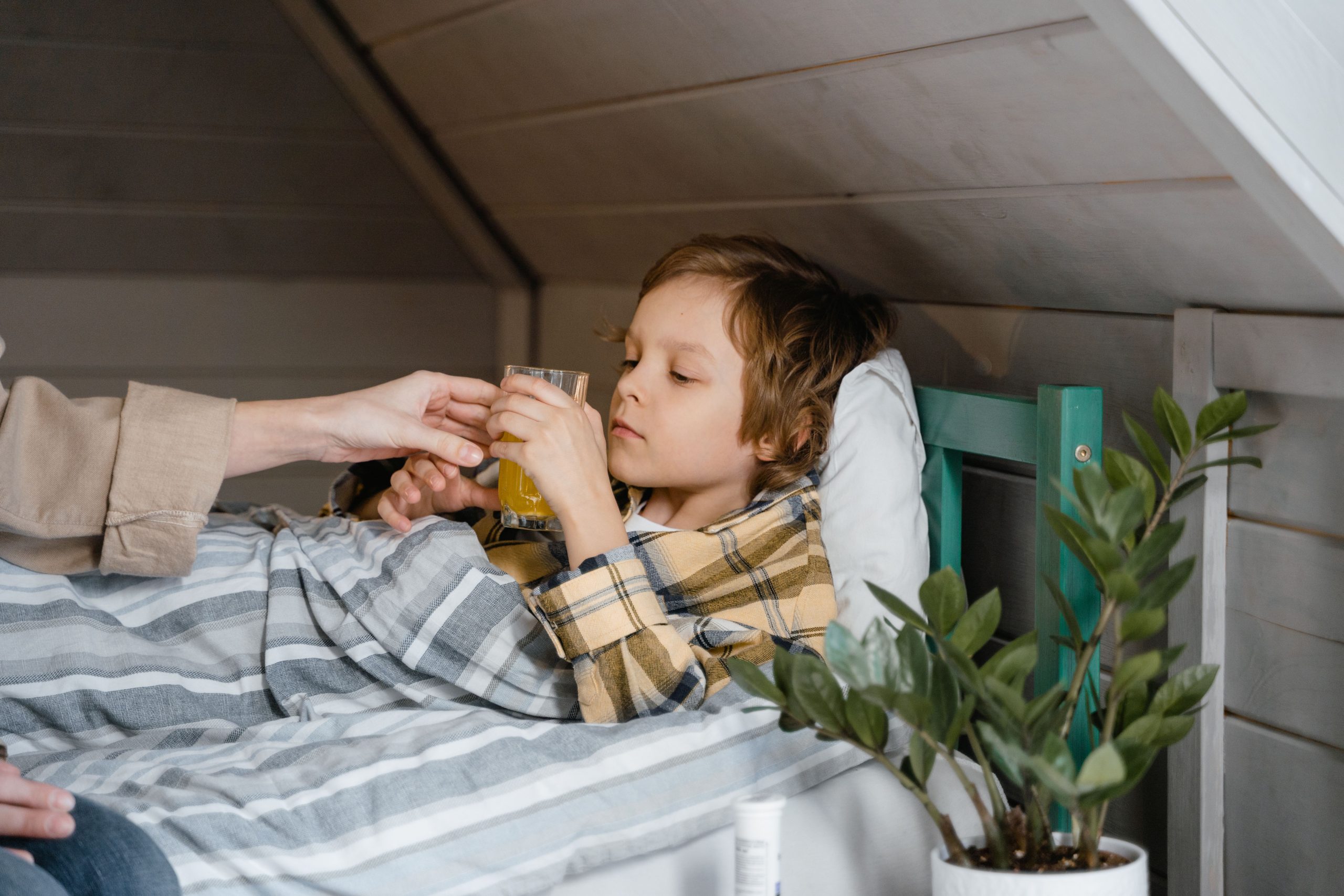 Enfant au lit buvant un verre de jus