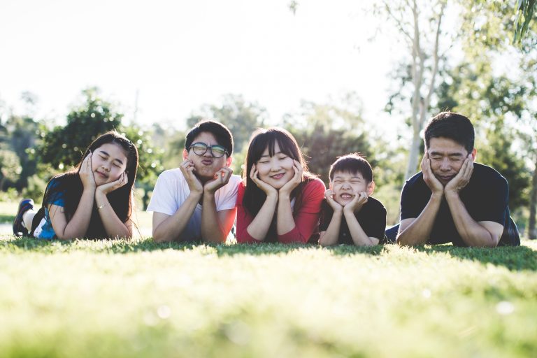 Famille asiatique heureuse sur l'herbe ensoleillée.