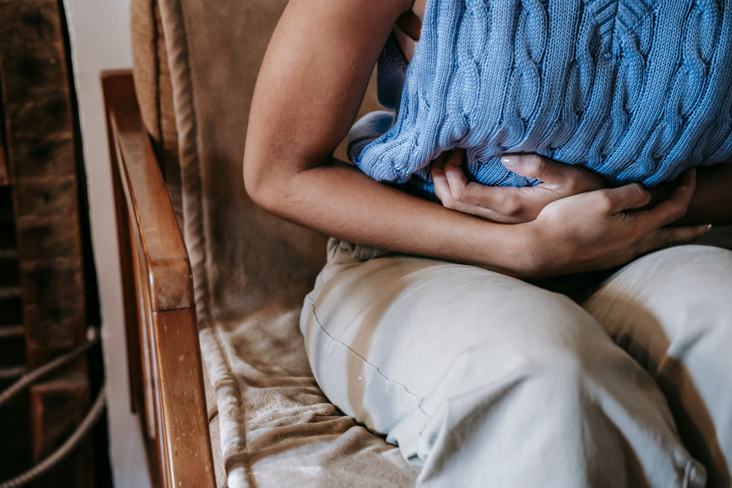 Femme assise canapé douleur abdominale aigue