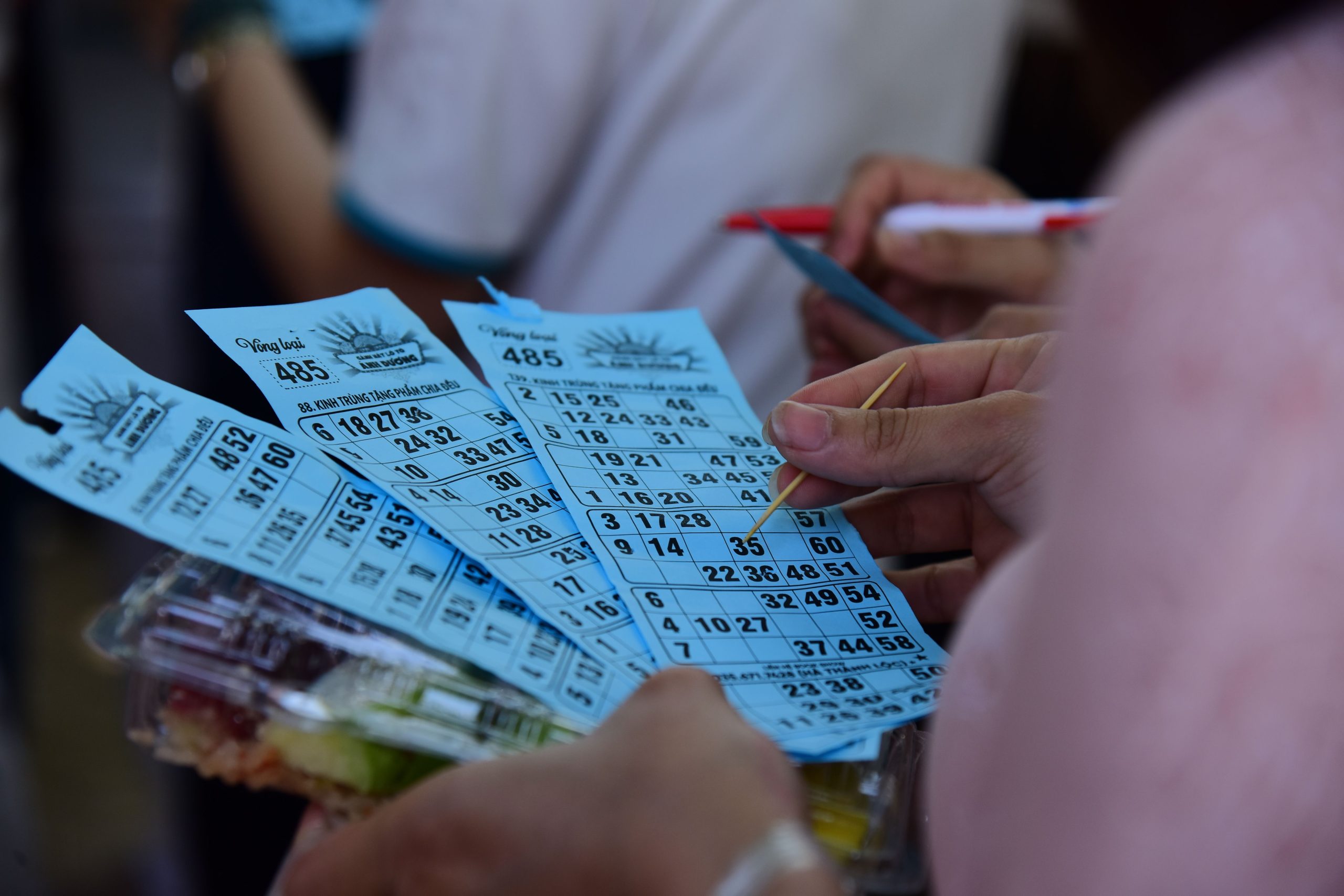 Joueurs de bingo tenant des cartes bleues et marqueurs