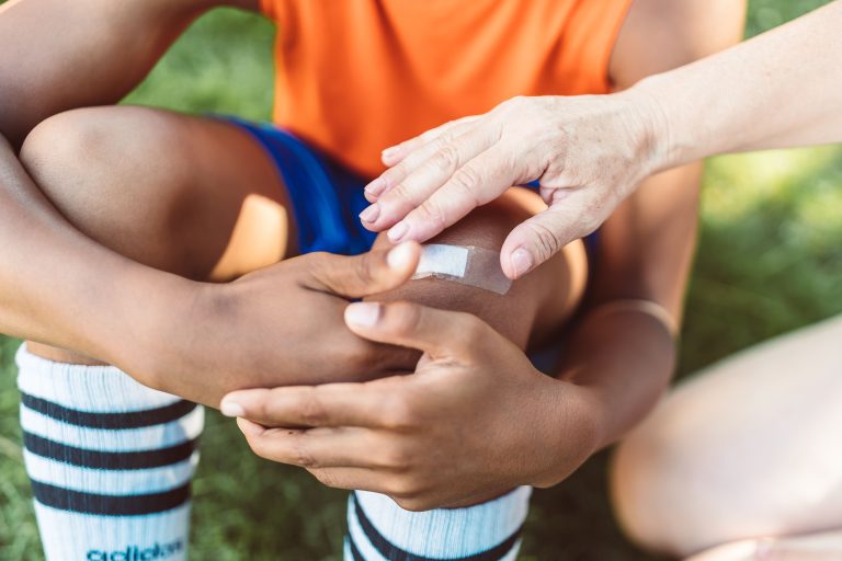 Adulte appliquant un pansement sur le genou d'un enfant