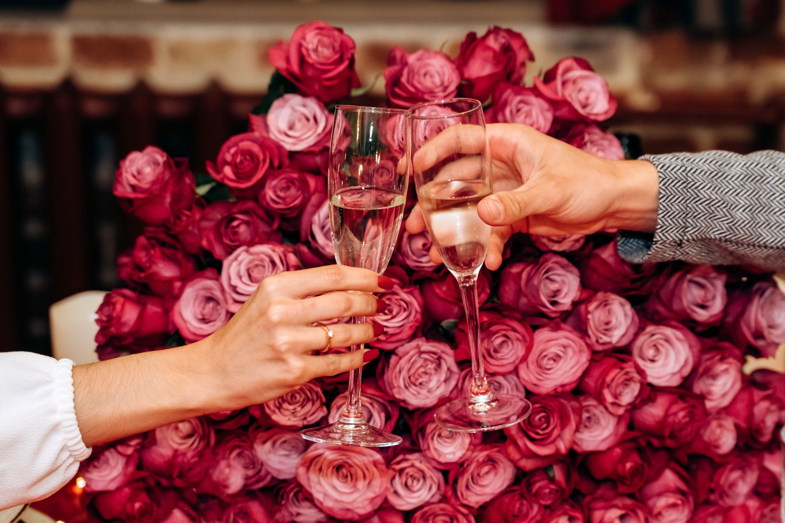 Deux personnes trinquant devant des roses