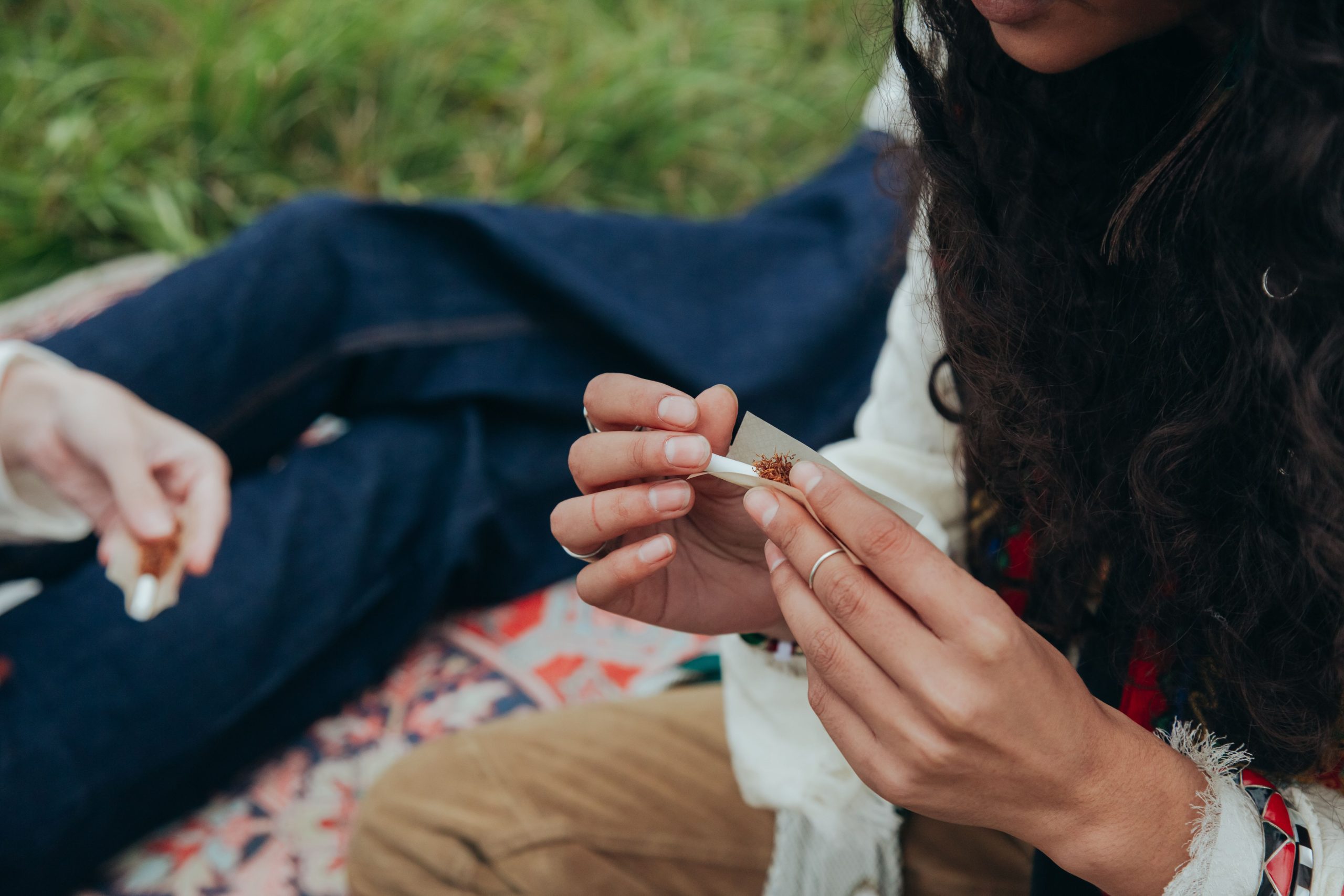 Mains roulant une cigarette sur un plaid en extérieur