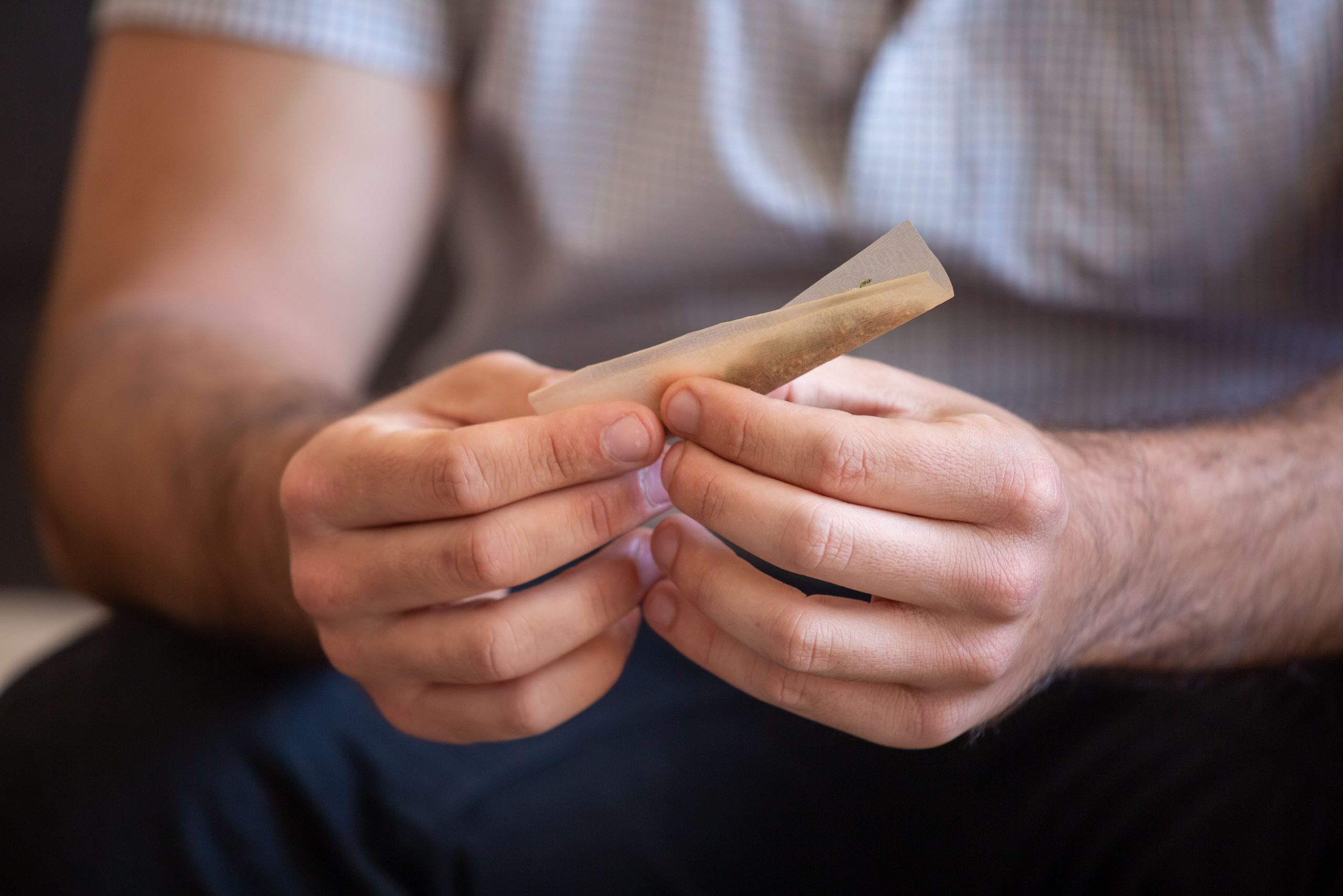 Homme concentré en train de rouler une cigarette