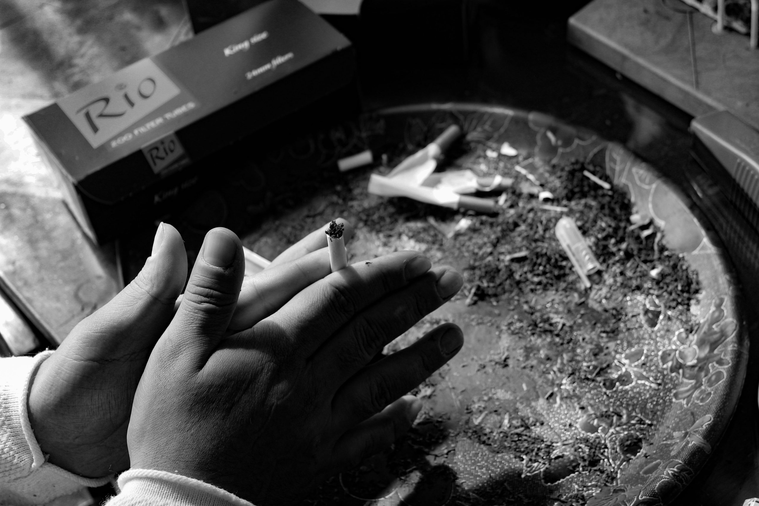 Gros plan en noir et blanc d'une main tenant une cigarette