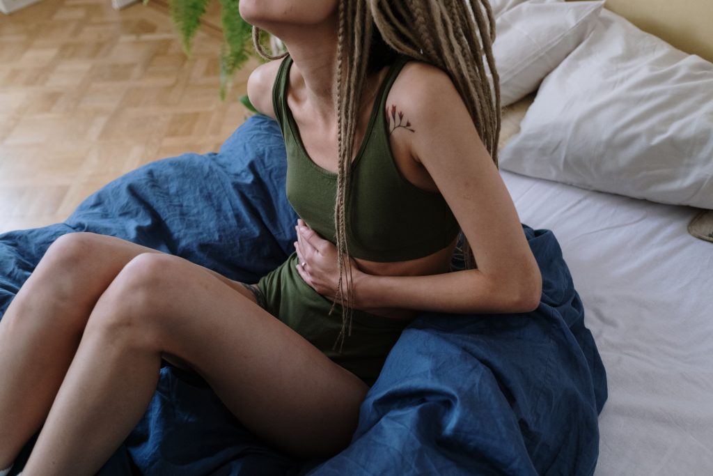 Femme assise au lit se tenant le ventre
