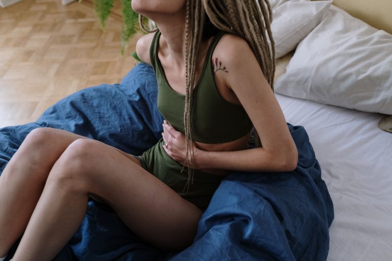 Femme assise au lit se tenant le ventre