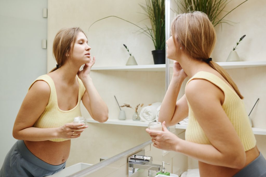 Femme enceinte applique crème soin visage miroir