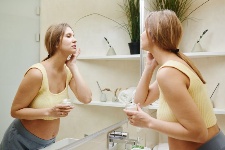 Femme enceinte applique crème soin visage miroir