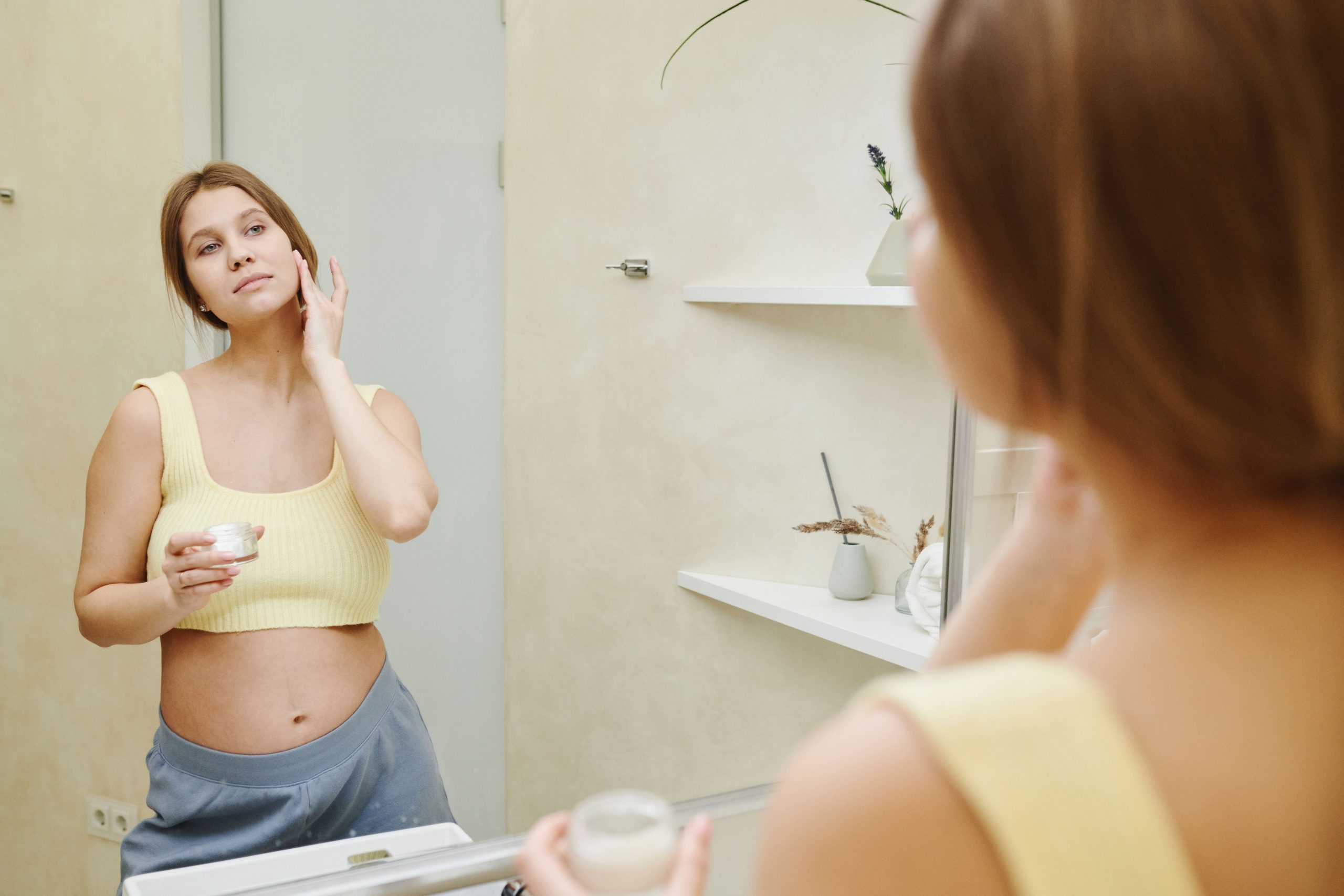 Femme enceinte utilise crème faciale salle bain