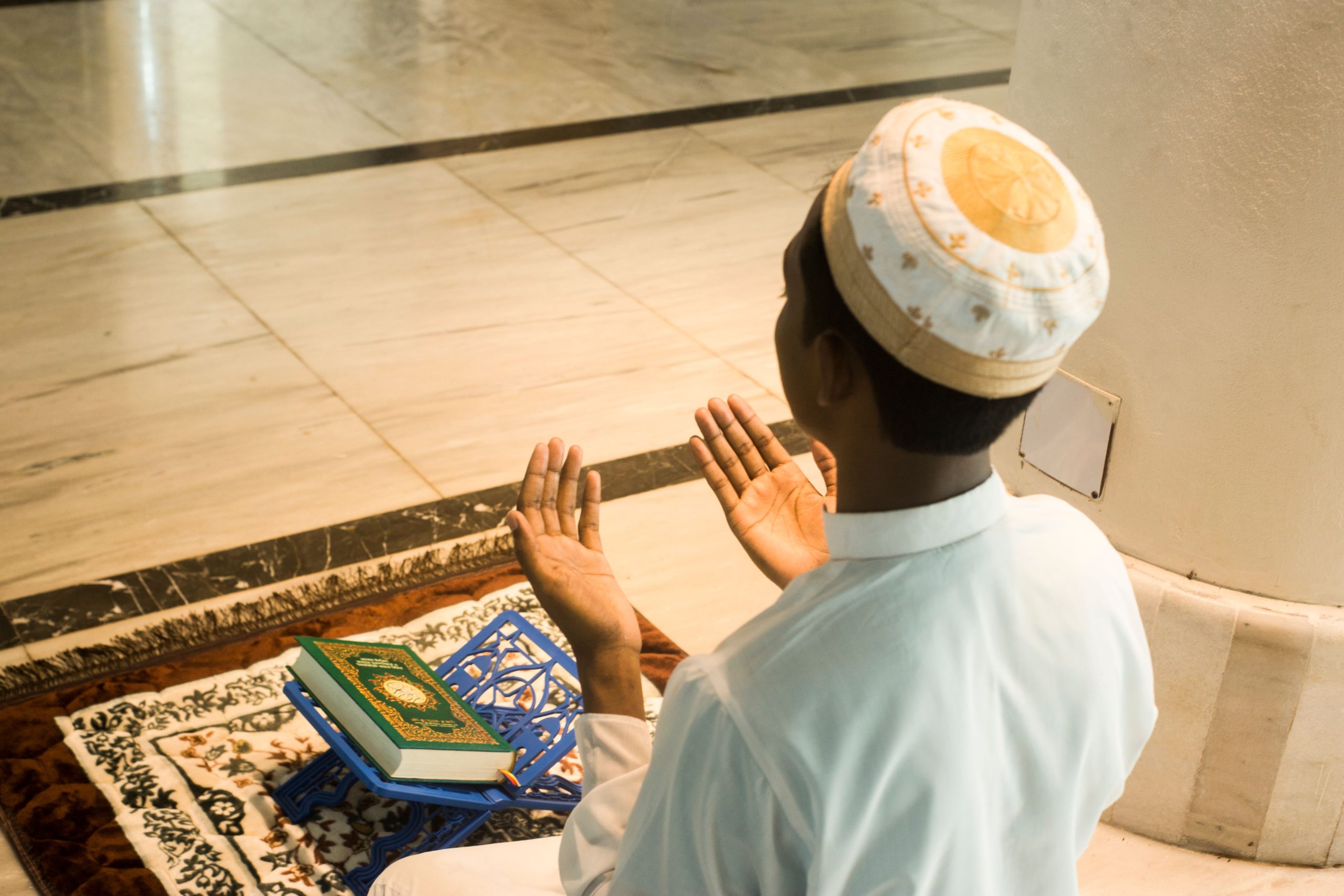 Jeune homme musulman priant avec le Coran