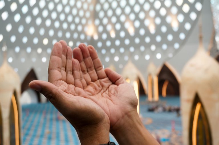 Mains levées en prière dans une mosquée illuminée