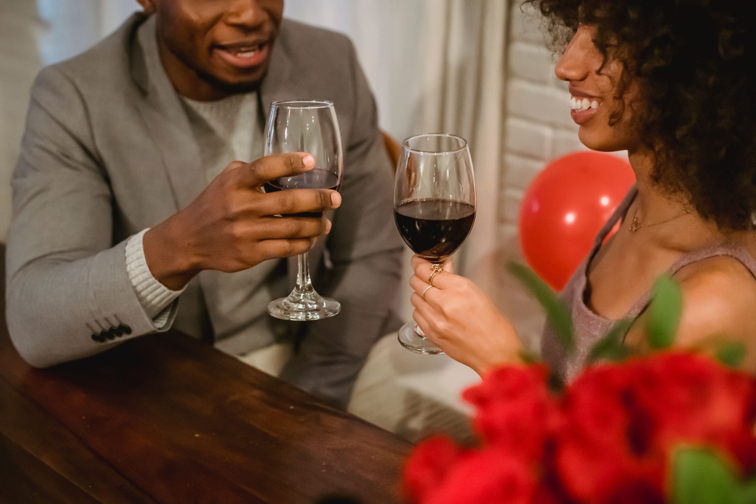 Couple trinquant avec verres de vin et fleurs.