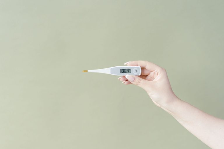 Main tenant thermometre digital affichant 36.4°C