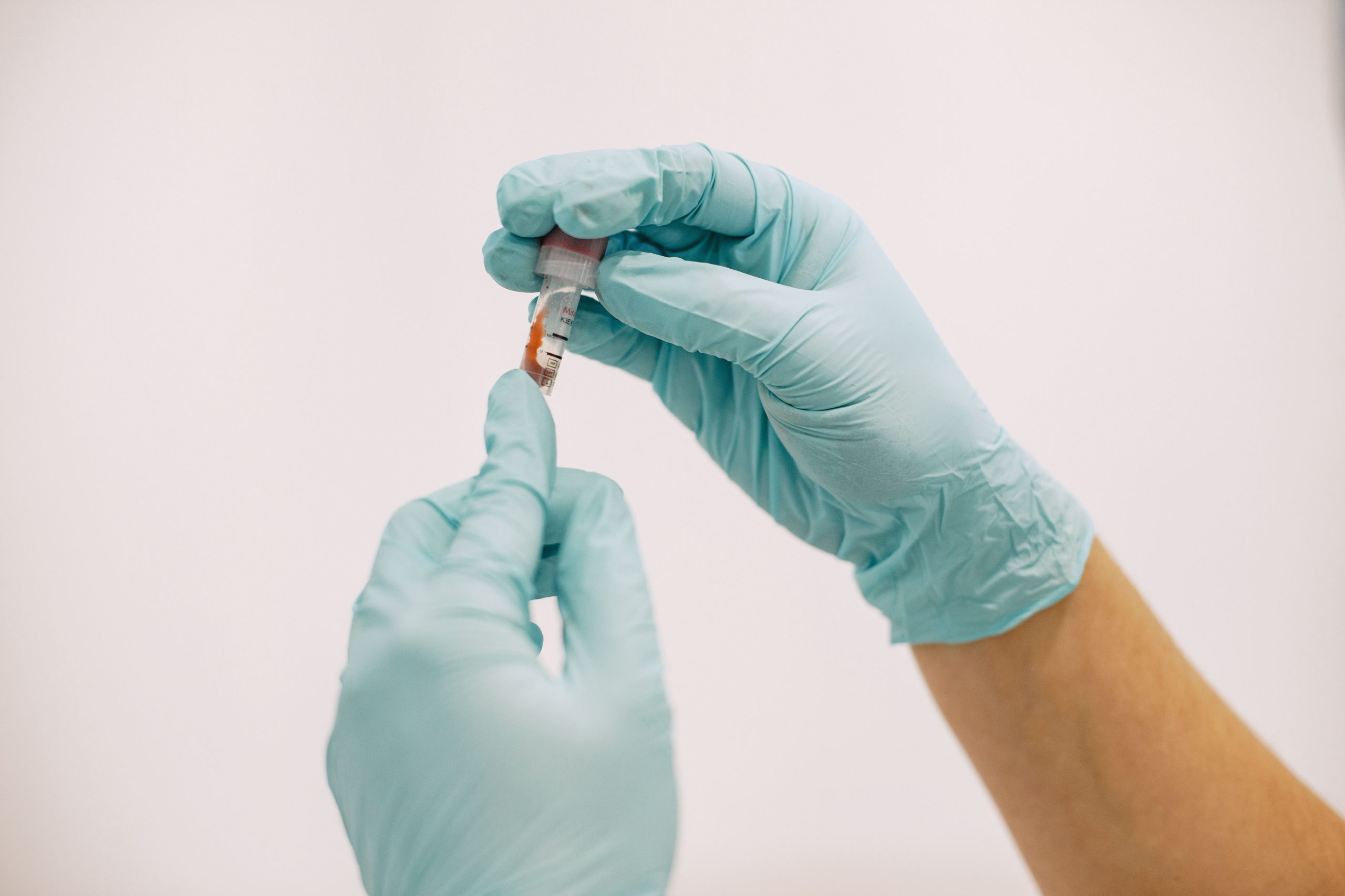 Mains gantées manipulant un tube d'essai en laboratoire